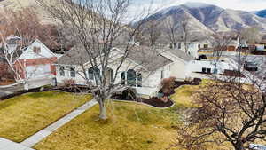 View of front of house with roof with shingles, a residential view, a front lawn, stucco siding, and a mountain view