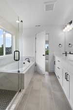 Full bath with a garden tub, a shower stall, double vanity, and light tile patterned floors