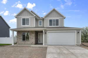 View of front of home with board and batten siding, a porch, concrete driveway, and an attached garage
