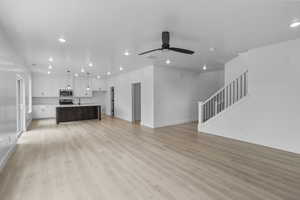 Unfurnished living room with recessed lighting, stairs, light wood-type flooring, and ceiling fan