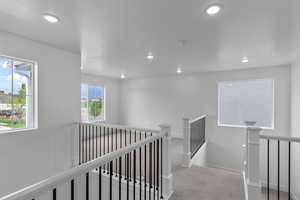 Hall featuring carpet flooring, an upstairs landing, and recessed lighting