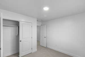 Unfurnished bedroom with light colored carpet and a closet