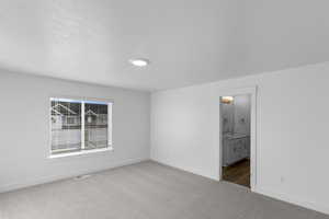 Unfurnished bedroom featuring light carpet and connected bathroom