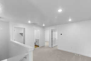 Hall featuring light carpet, recessed lighting, and an upstairs landing
