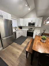 Kitchen featuring stainless steel appliances, white cabinetry, light countertops, light wood finished floors, and a textured ceiling