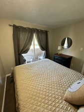 Bedroom with a textured ceiling and baseboards