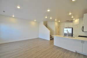 Open Space Living Room, Dining Room and Kitchen, with white cabinets, a peninsula, appliances with stainless steel finishes, light wood-type flooring, and open floor plan