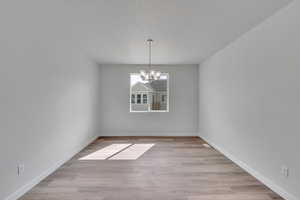 Unfurnished dining area with light wood-type flooring and a chandelier