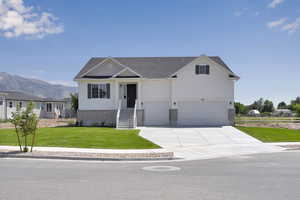 View of front of house with concrete driveway, a front lawn, an attached garage, a mountain view, and brick siding