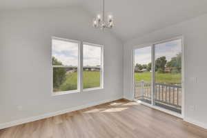 Unfurnished dining area featuring a chandelier, light wood-style floors, and lofted ceiling