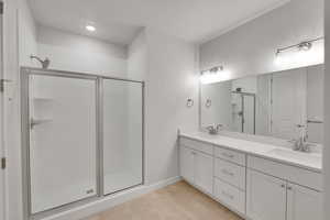 Bathroom with a stall shower, double vanity, light tile patterned floors, and recessed lighting