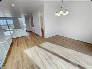 Unfurnished dining area featuring light wood-type flooring, recessed lighting, and a chandelier