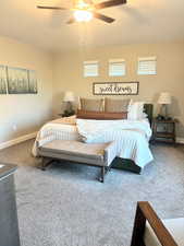 Carpeted bedroom with a ceiling fan and multiple windows