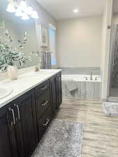 Full bathroom with double vanity, a bath, dark wood finished floors, and a shower stall