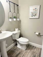 Half bath featuring toilet and wood finished floors