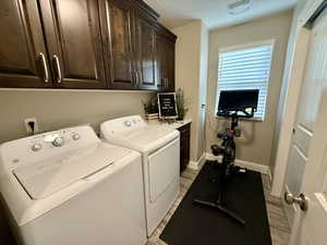 Laundry room featuring cabinet space, washer and clothes dryer, and light wood finished floors