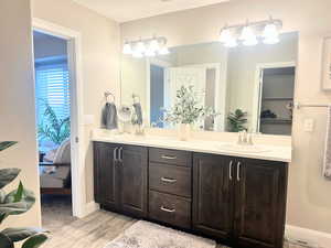 Ensuite bathroom featuring double vanity and light wood-style floors