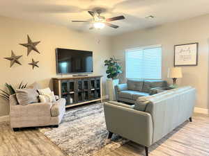 Living room with light wood finished floors and a ceiling fan