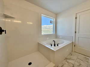 Bathroom featuring a garden tub and marble finish floors