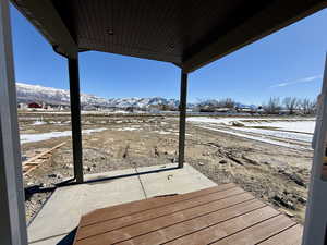 Snow covered deck featuring a mountain view and a patio