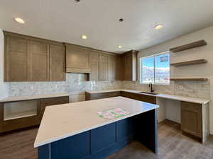 Kitchen featuring tasteful backsplash, a center island, light stone counters, recessed lighting, and open shelves