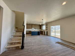 Staircase with hanging lights, wood finished floors, and a textured ceiling
