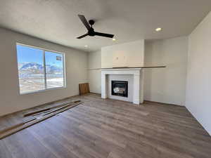 Unfurnished living room with a mountain view, a ceiling fan, wood finished floors, a textured ceiling, and recessed lighting