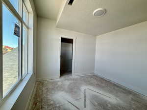 Unfurnished bedroom featuring a walk in closet and a textured ceiling
