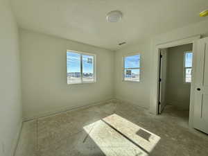 Empty room with a textured ceiling and a smoke detector