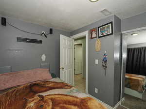 Bedroom featuring a textured wall and a textured ceiling