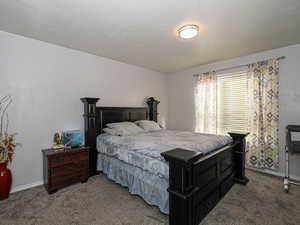 Carpeted bedroom with a textured ceiling and baseboards
