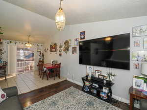 Living room with hardwood / wood-style flooring, a chandelier, vaulted ceiling, and a textured ceiling