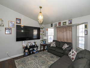 Living area with wood finished floors, vaulted ceiling, and a chandelier