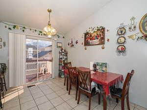 Dining space featuring light tile patterned floors, vaulted ceiling, and a chandelier