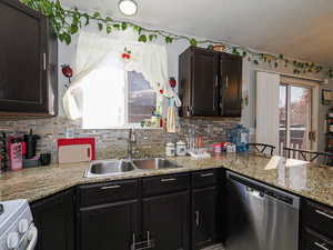 Kitchen with stainless steel dishwasher, white range, a peninsula, dark brown cabinets, and tasteful backsplash