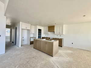 Two tone kitchen featuring a kitchen island, dual tone cabinets, and a textured ceiling