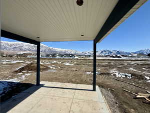 Snow covered patio featuring a mountain view and a patio area