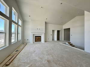 Unfurnished living room featuring a fireplace and lofted ceiling