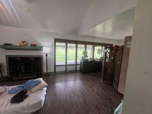 Living area featuring a fireplace, dark wood-type flooring, and lofted ceiling