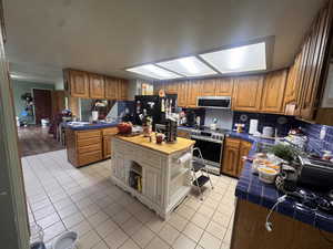 Kitchen featuring tile counters, wood finish cabinetry, and stainless steel appliances