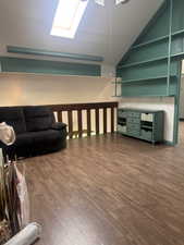 Living area with dark wood-type flooring, a skylight, and vaulted ceiling