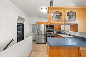 Kitchen featuring appliances with stainless steel finishes, glass insert cabinets, lofted ceiling, dark countertops, and a peninsula