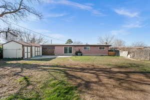 Back of house featuring a shed, brick siding, a patio area, and a chimney