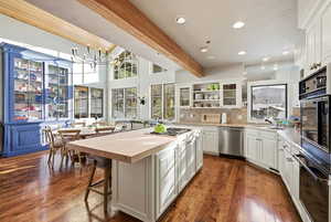 Kitchen featuring beam ceiling, wood counters, stainless steel appliances, open shelves, and white cabinets