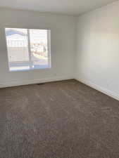 Spare room featuring dark colored carpet and baseboards