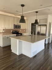 Kitchen featuring hanging light fixtures, decorative backsplash, a large island, appliances with stainless steel finishes, and a textured ceiling