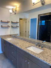 Bathroom featuring double vanity, a stall shower, light tile patterned floors, and a textured ceiling