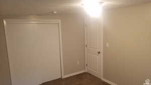 Empty room featuring dark carpet and a textured ceiling