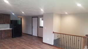 Kitchen featuring black fridge with ice dispenser, dark brown cabinetry, dark wood-style flooring, and recessed lighting