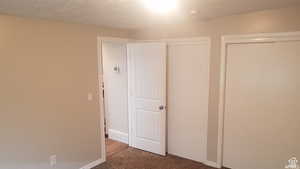 Unfurnished bedroom with dark carpet, a closet, and a textured ceiling
